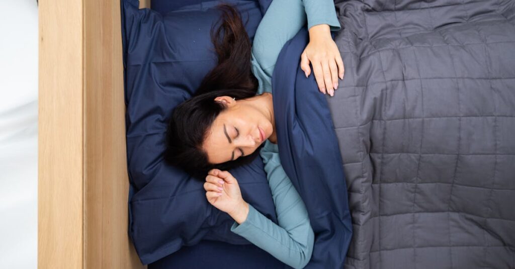 A woman peacefully sleeping under a cozy, dark blue bedding set in a serene bedroom environment.