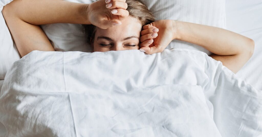 Woman comfortably resting in bed, enjoying a peaceful morning under the covers.